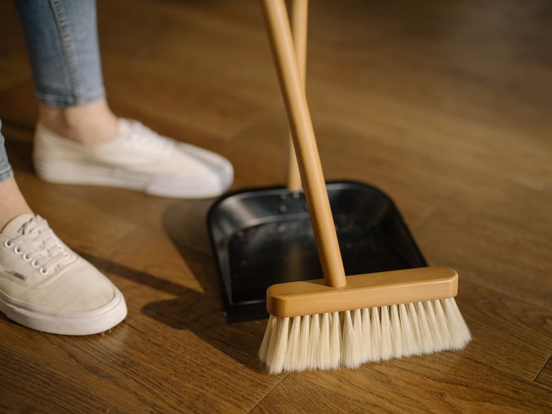 Wooden broom and dustpan on wooden floor — friendly domestic cleaning detail