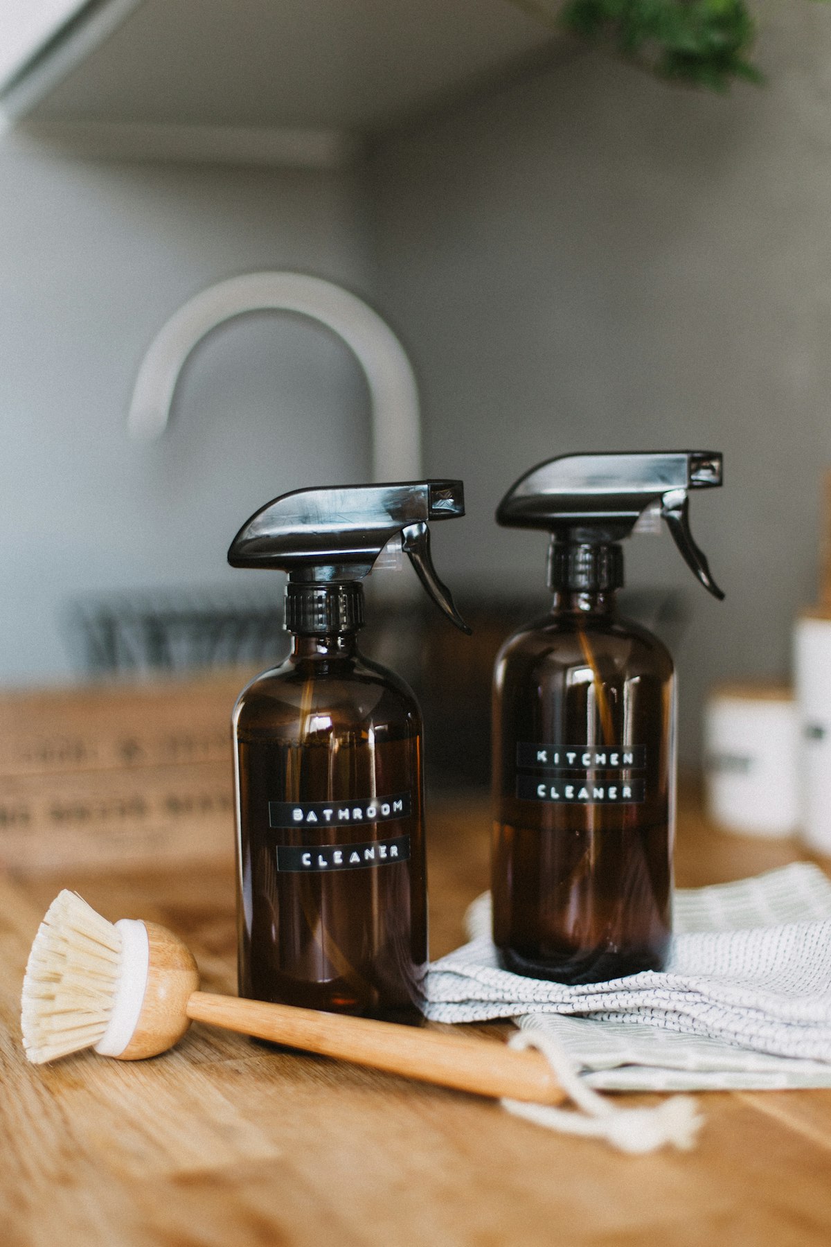 Labelled bathroom and kitchen spray bottles with scrubbing brush