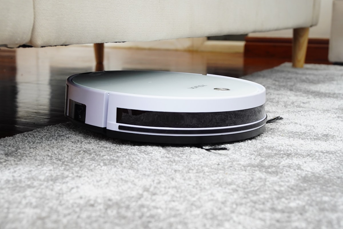 Vacuum cleaner on grey rug under a sofa