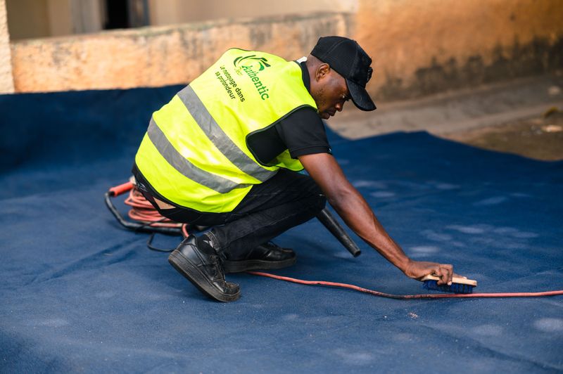 Professional cleaner scrubbing a deep blue carpet outdoors with a brush — thorough carpet cleaning in Rolleston