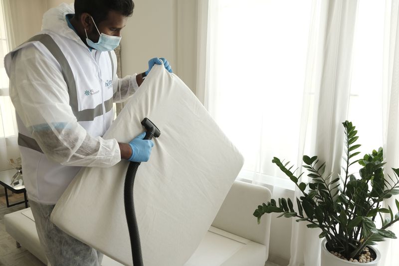 Mattress cleaning — professional vacuuming with protective gear