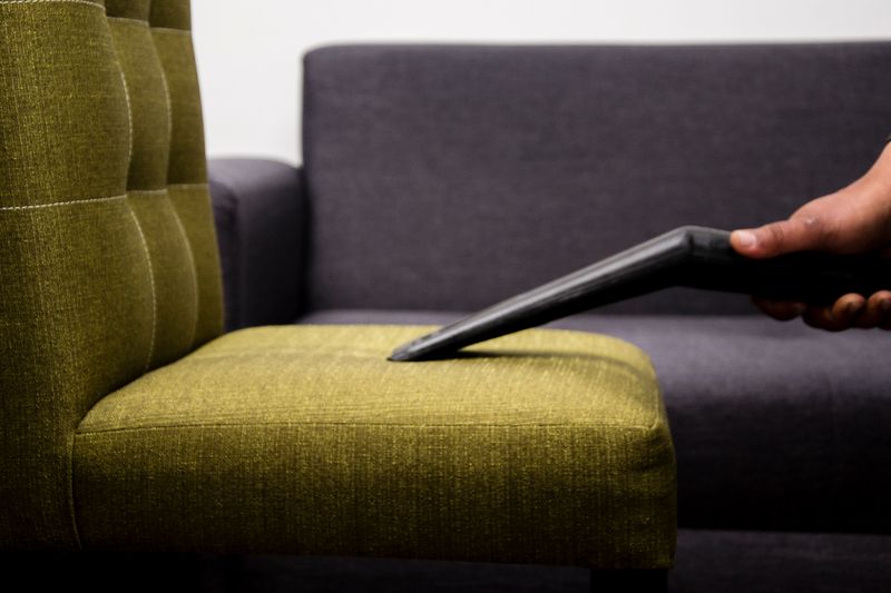 Upholstery cleaning — vacuuming a modern sofa chair
